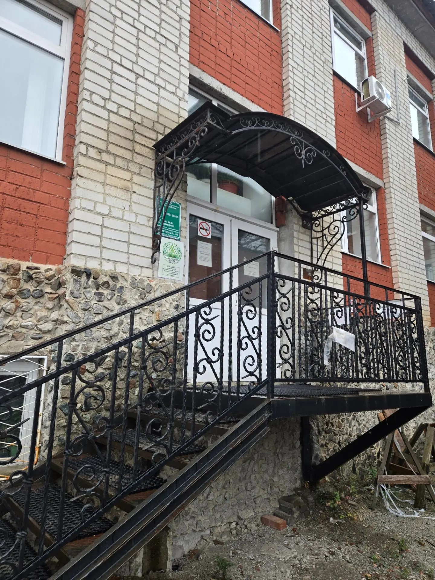 Вход в здание с металлическим навесом и лестницей