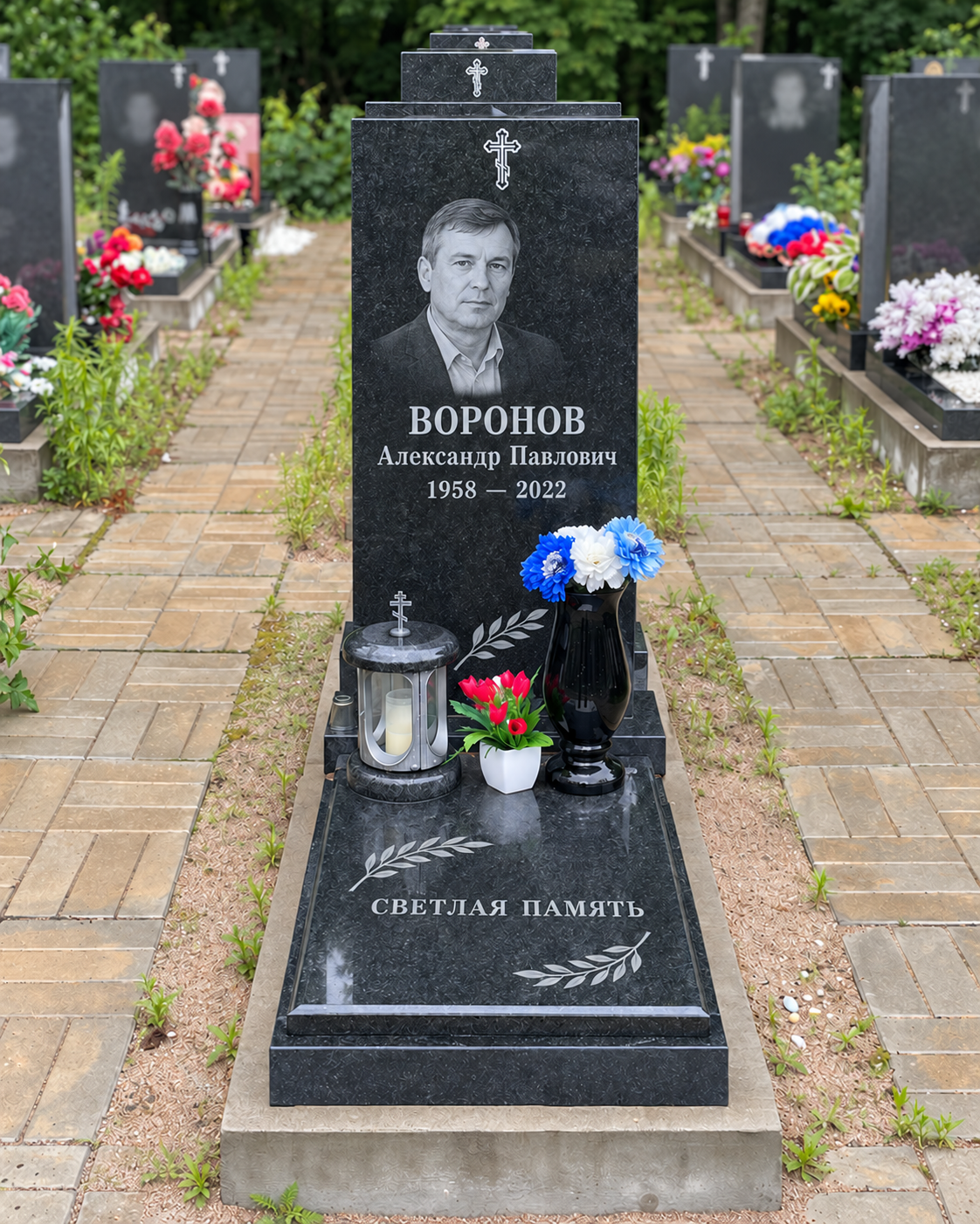Памятник с плитой, вазой и лампадой после установки на участке. Имена, даты и портреты изменены.
