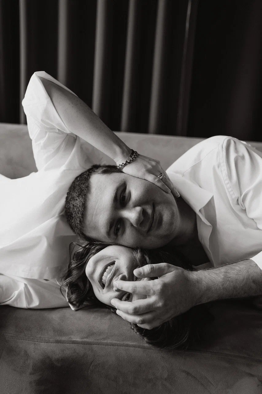 Чёрно-белый портрет пары, которая обнимается лёжа на диване во время домашней фотосессии Love Story