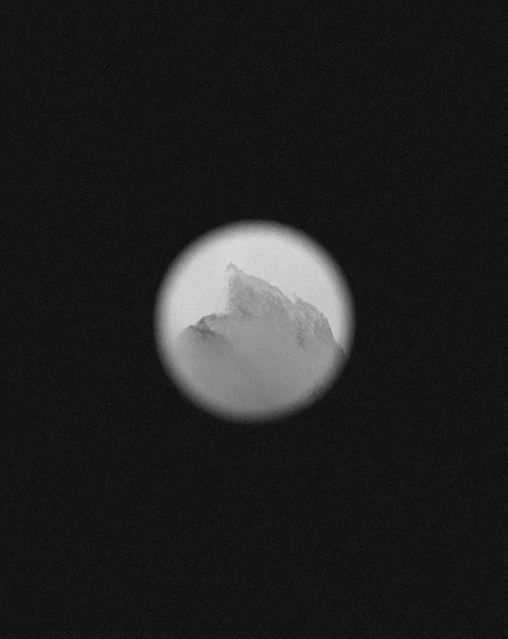 Snow-covered Antarctic mountain seen through binoculars during a polar expedition.