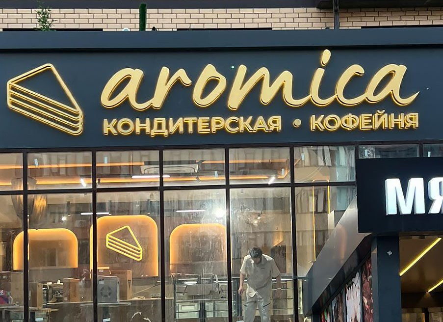 Объемные буквы из черного глянцевого акрила с алюминиевыми бортами и контражурной подсветкой на фоне серебристого композита. В светлое время - стильно и серьёзно. В темное время суток - яркий контур вокруг букв!