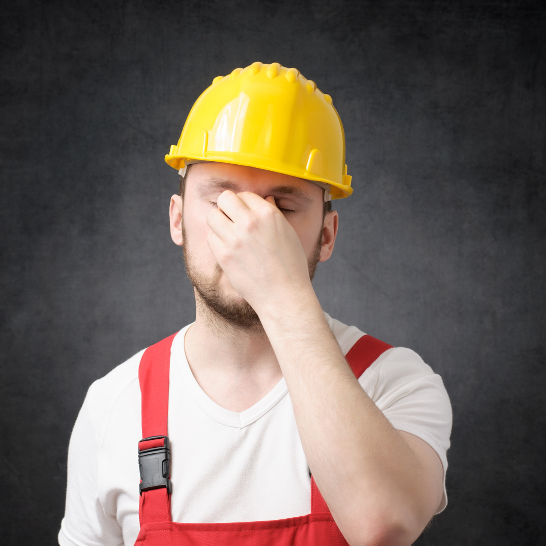 a person in a hard hat covering their face with their hand