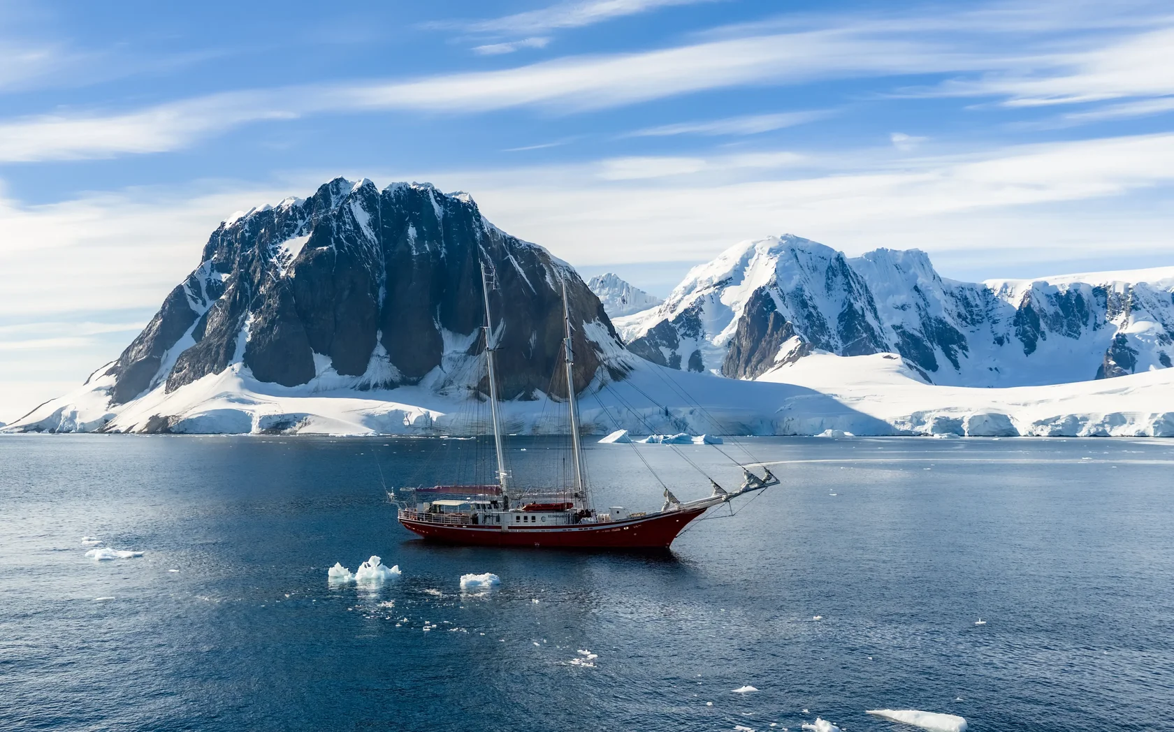 The schooner Eldorado sailing through the spectacular waters of Antarctica, surrounded by snow-covered mountains, glaciers and drifting ice. Operated by MoreTime Expeditions, Eldorado offers small-group sailing expeditions and an intimate way to explore the remote landscapes of the Antarctic Peninsula.