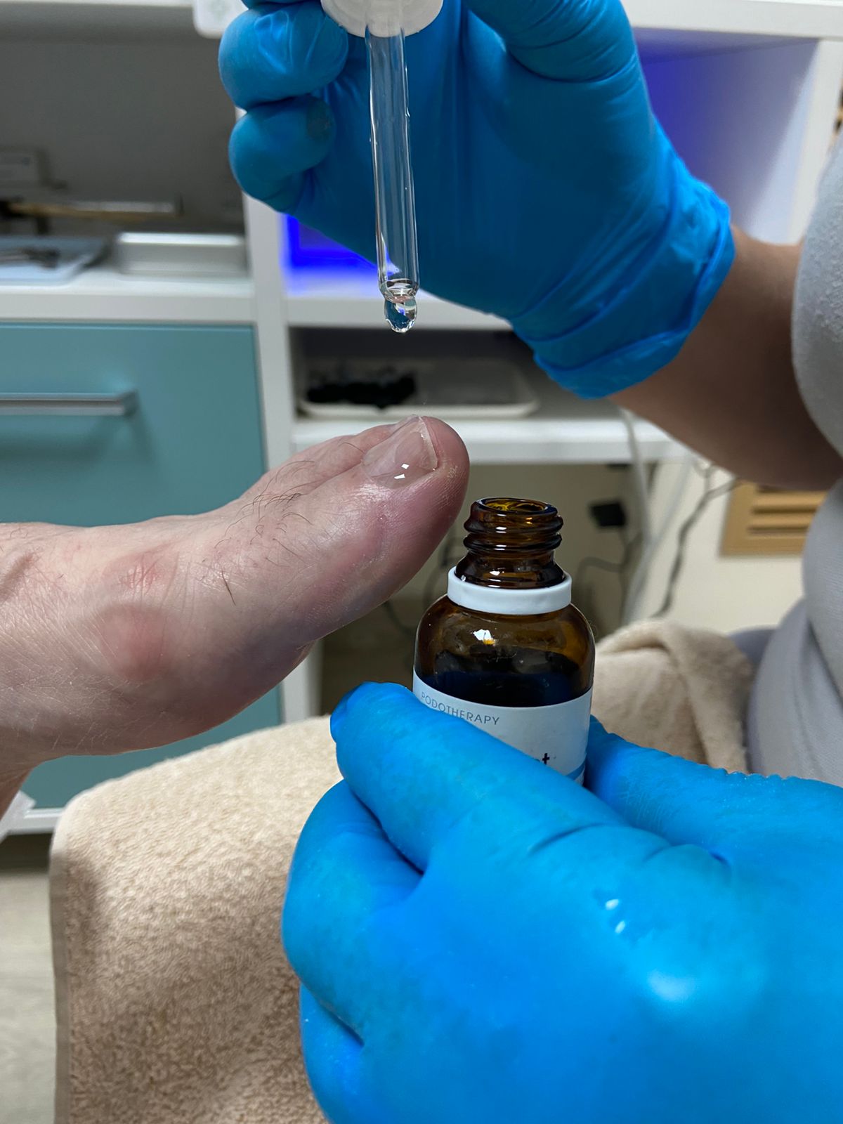 Врач-подолог наносит средство для восстановления ногтя и ногтевого ложа