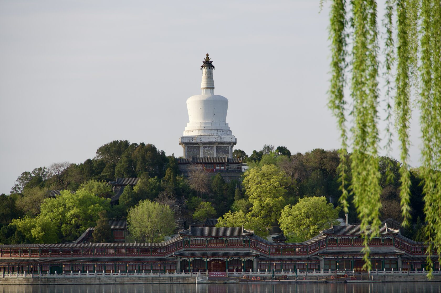 Белая пагода (White Dagoba) в парке Бэйхай, Пекин — вид через озеро и ивы