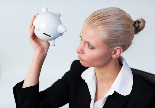 Sad Business woman looking into Piggy Bank