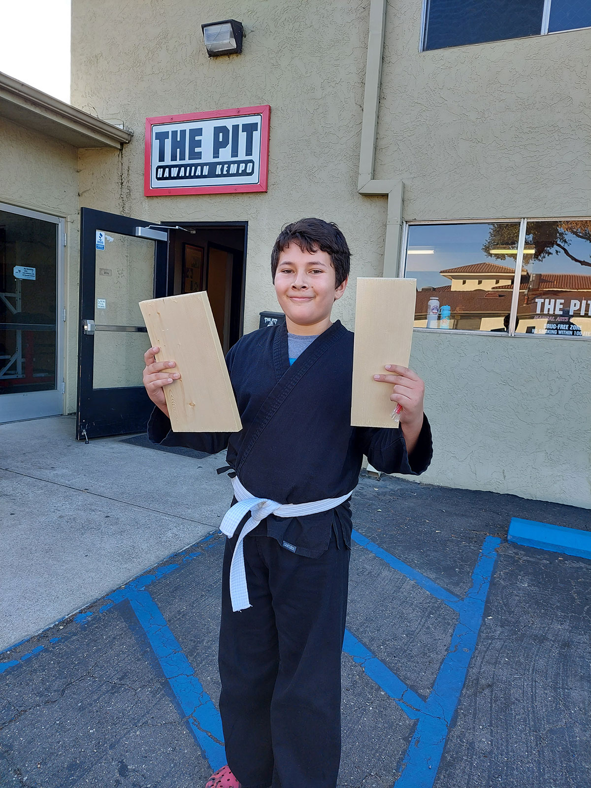 Eddie Fischer holding broken boards after belt testing The Pit Martial Arts.