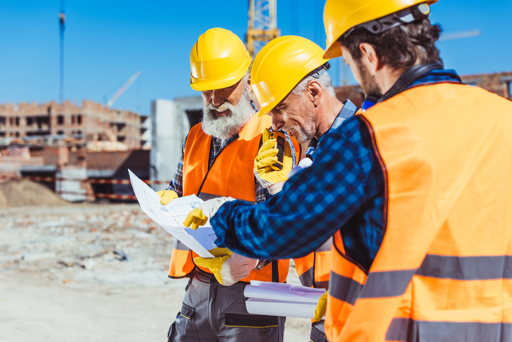 Проверка конструкций. Два строителя обсуждают машины. Three workers.