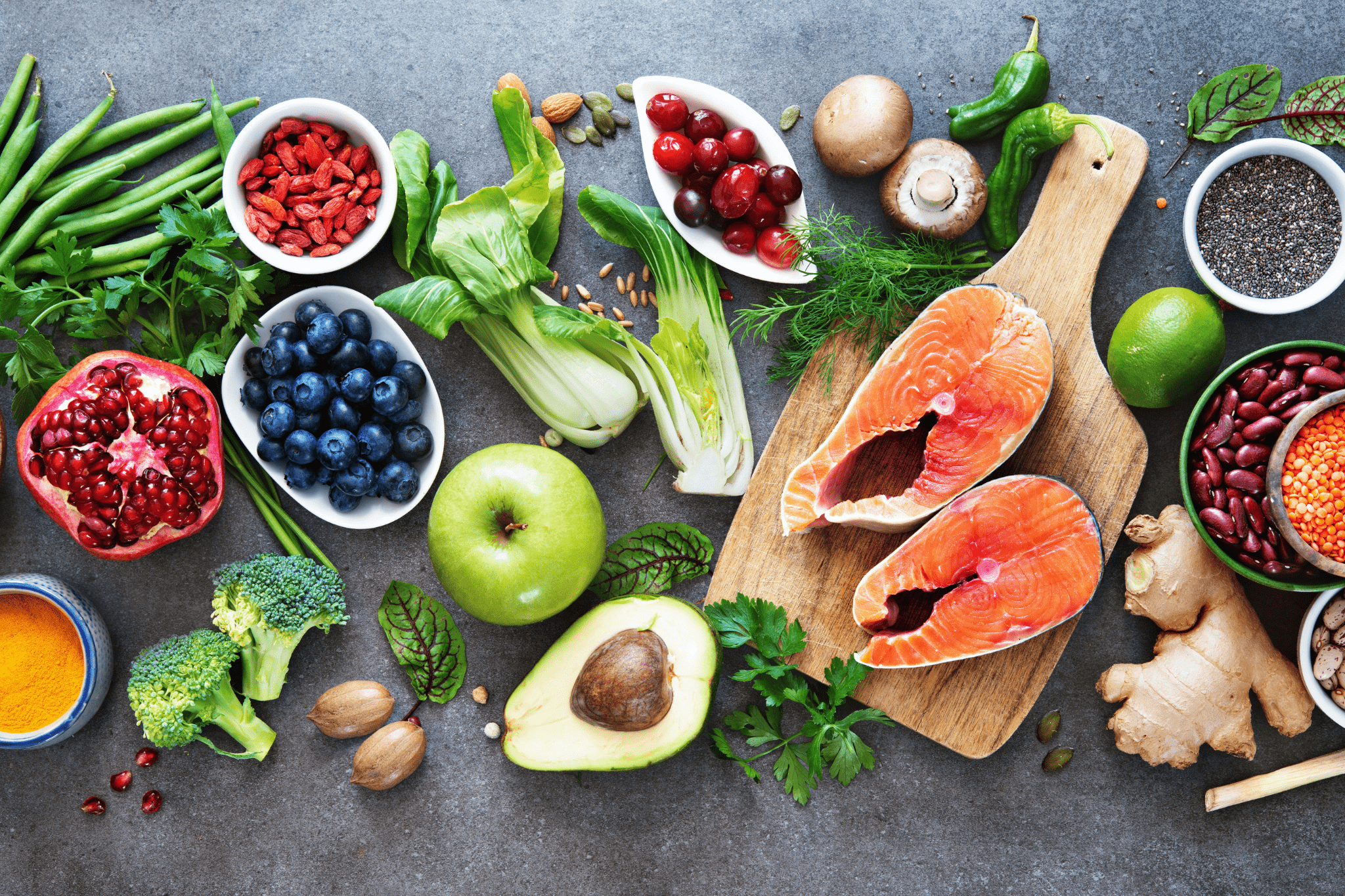 Gesunde Lebensmittel wie Obst, Gemüse, Fisch und gesunde Fette auf grauem Hintergrund