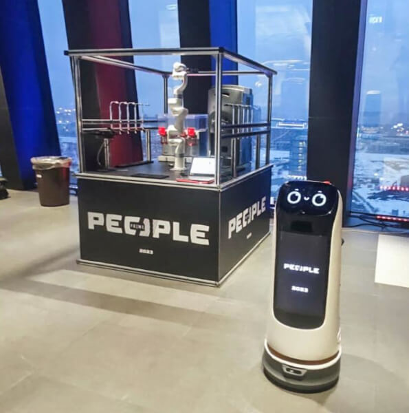 Электронный помощник KettyBot демонстрирует рекламный ролик на экране среди посетителей