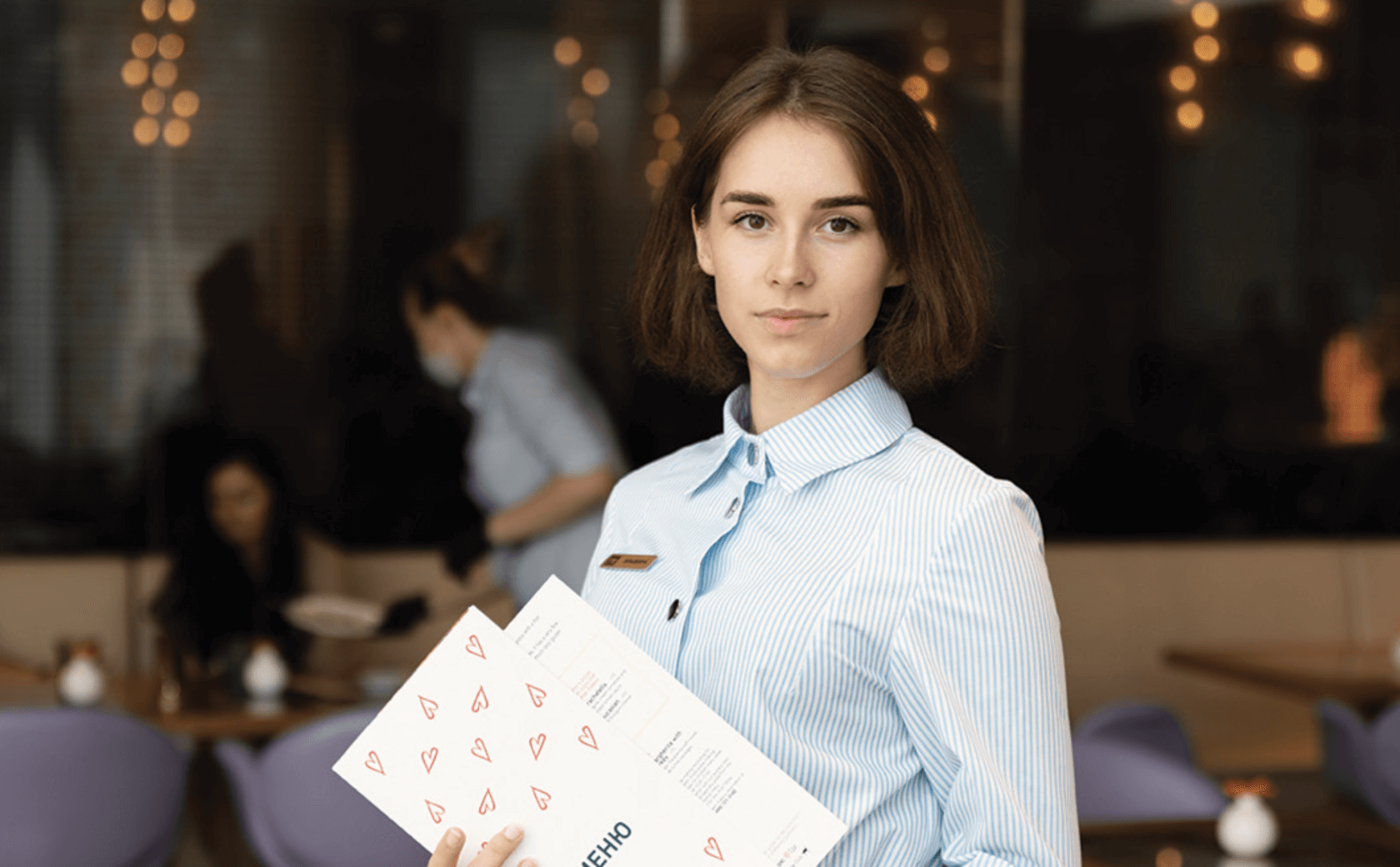 Ученица бариста с меню в руках в уютной кофейне