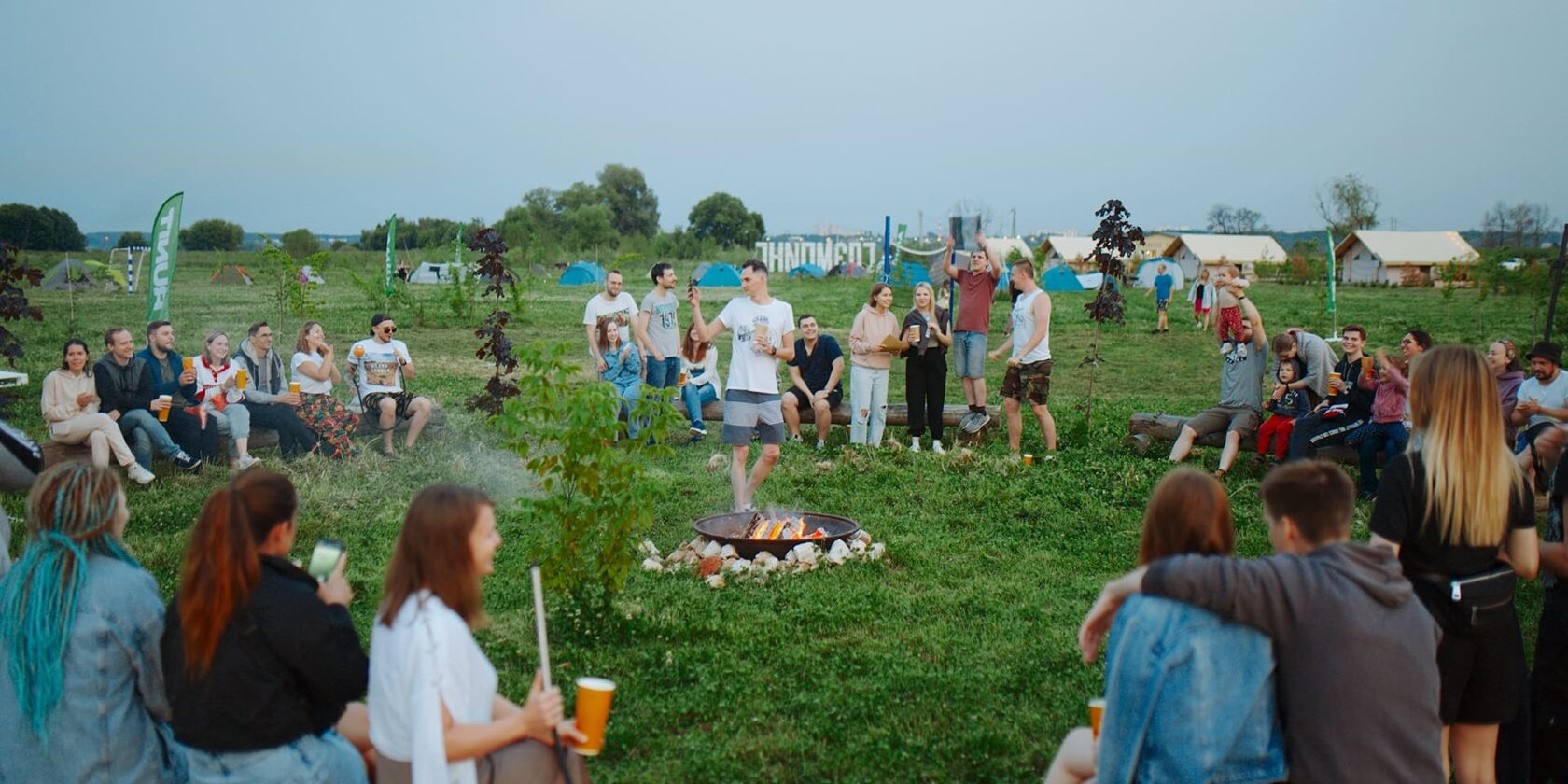 Guests gathered around the fire on the lawn at an Ostrov Glamping celebration