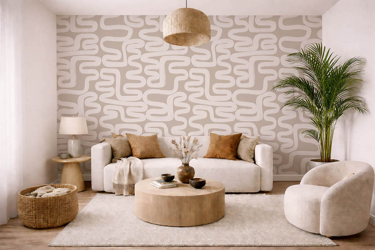Светлая гостиная в бежевых тонах с белым диваном, декоративными подушками, круглым деревянным журнальным столиком, креслом, напольным растением и акцентной стеной с геометрическим узором