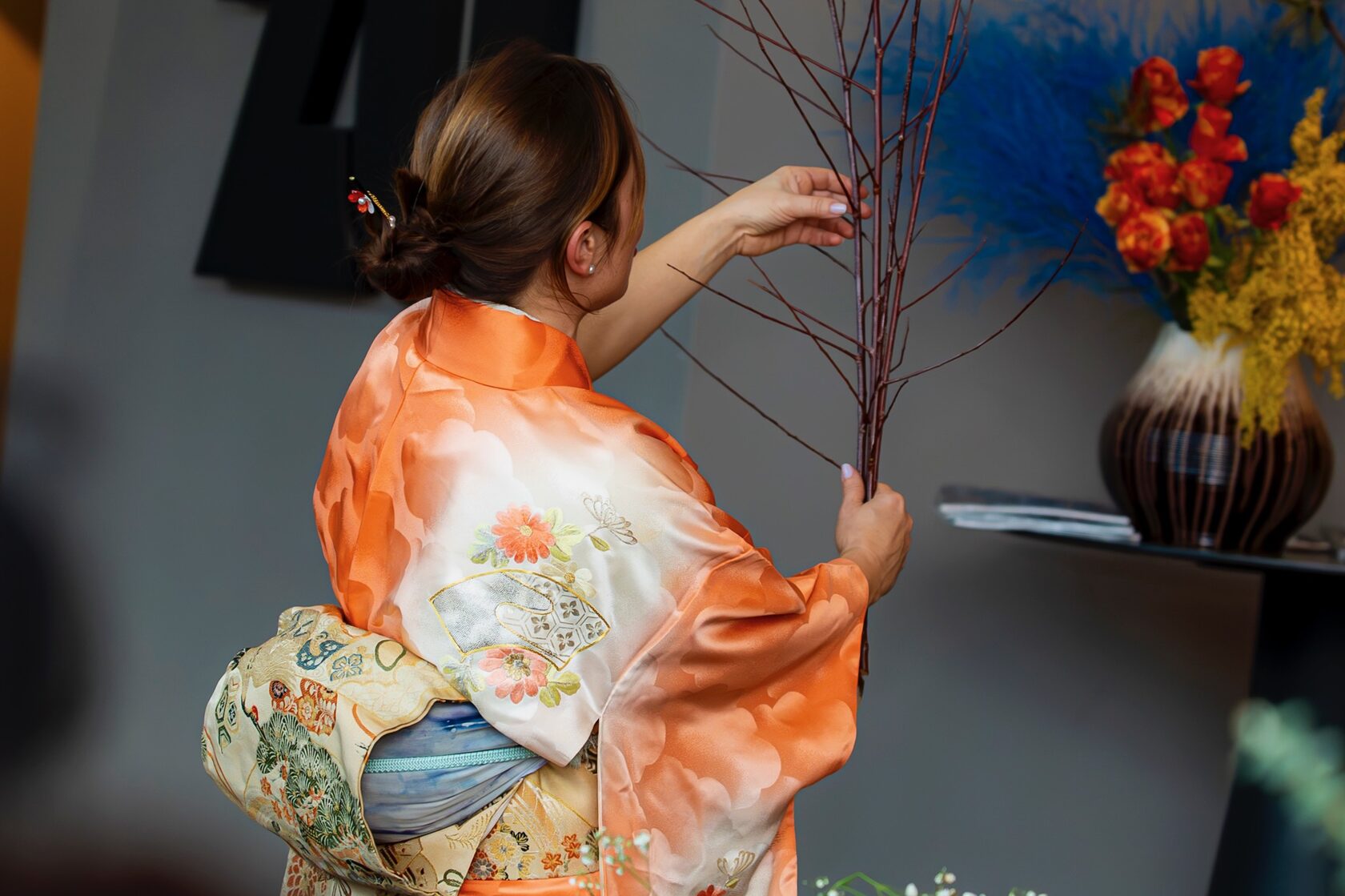 Дама в японско кимоно демонстрира изкуството на ikebana с подреждане на клони и цветя пред дамите от „Великолепната жена“.