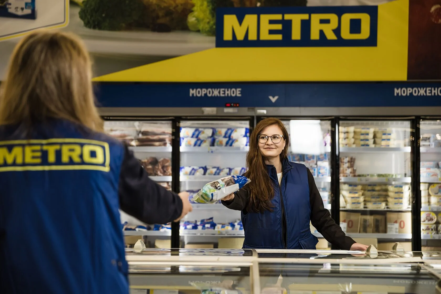 Сборщик передаёт товар в торговом зале METRO
