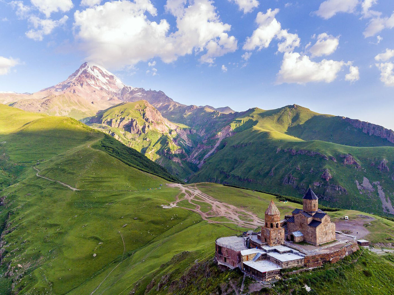 Gergeti church on a green ridge with the snowy cone of Kazbek behind it
