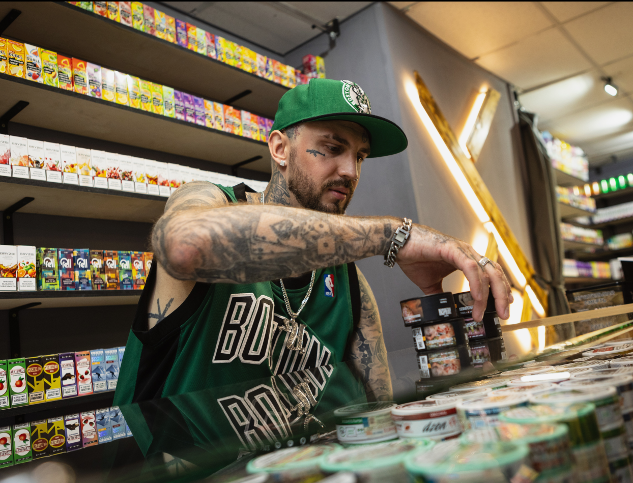 Мужчина в кепке смотрит на товар в вейпшопе SMOKESTAR