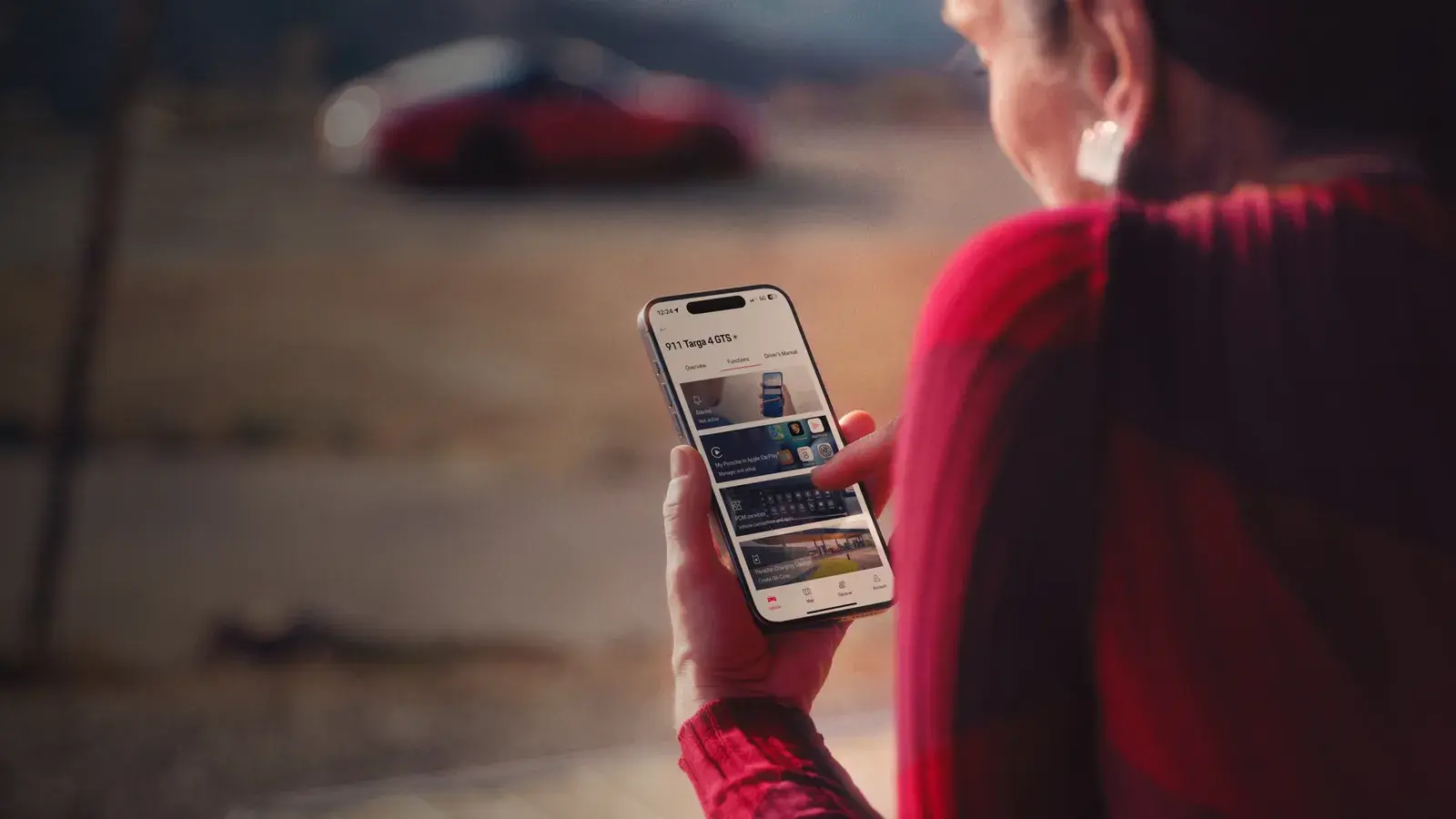 Женщина смотрит на смартфон с Porsche Connect