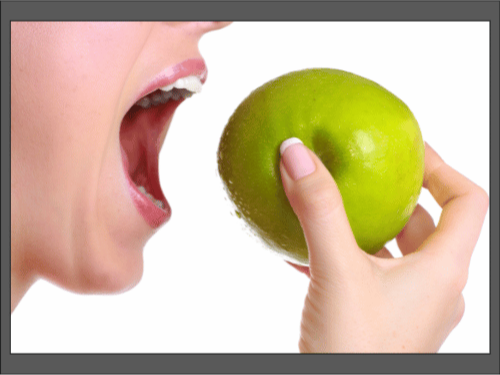 Человек собирается откусить зелёное яблоко крупным планом.