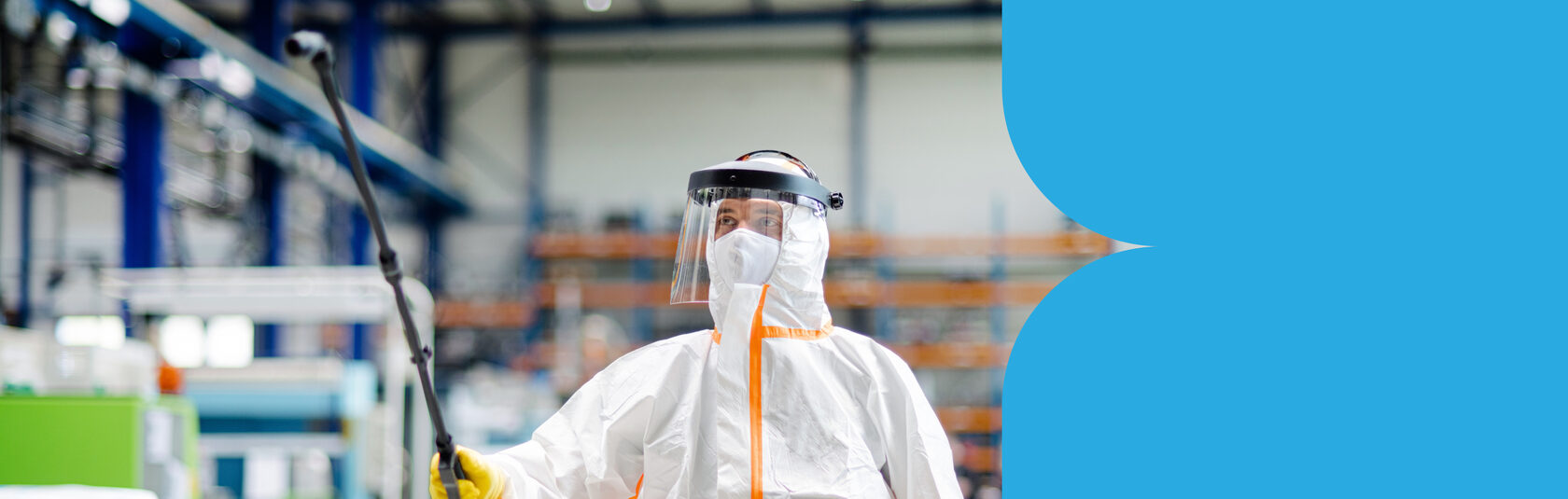 Сотрудник в защитном костюме проводит дезинфекцию помещения