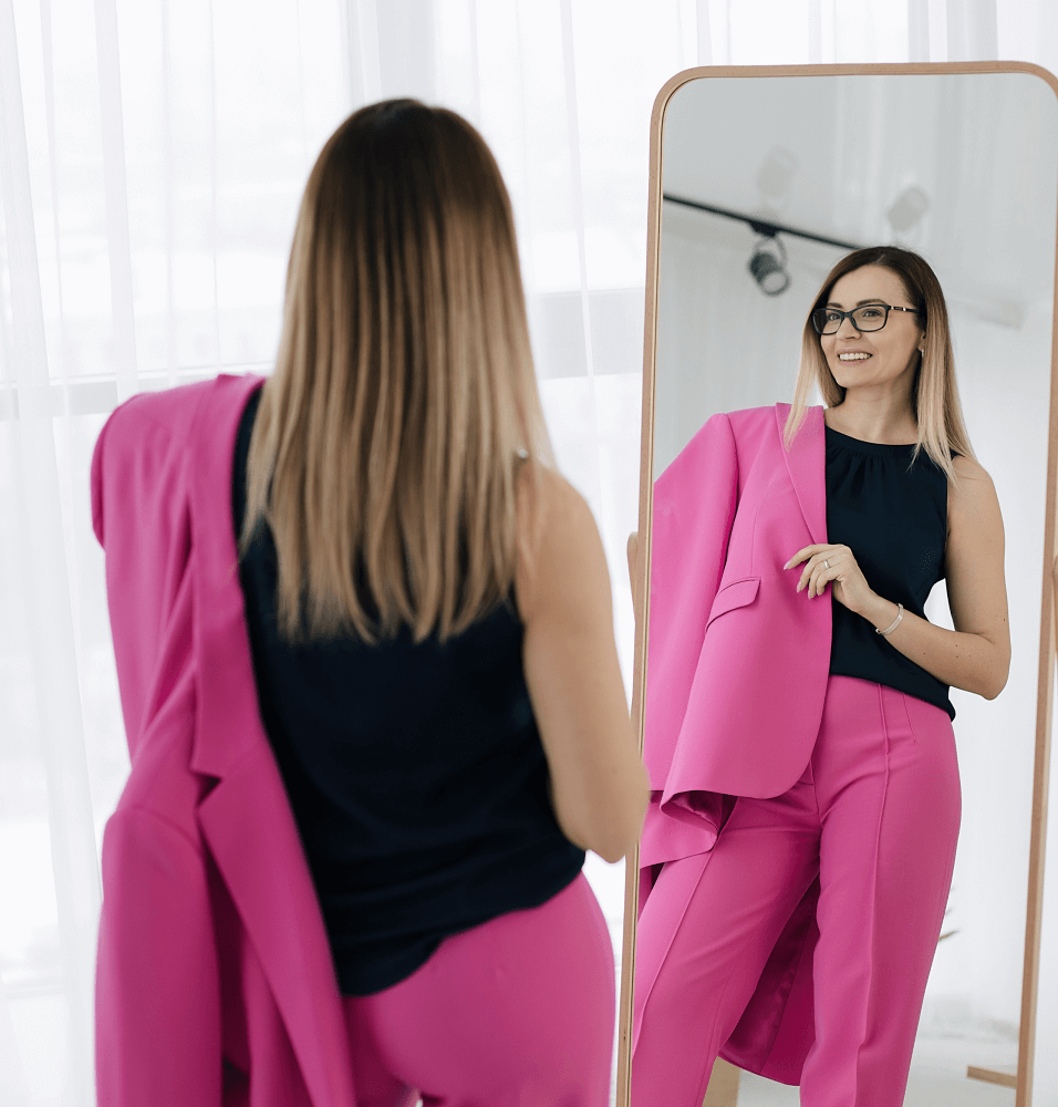 Девушка смотрит на себя в зеркало и улыбается