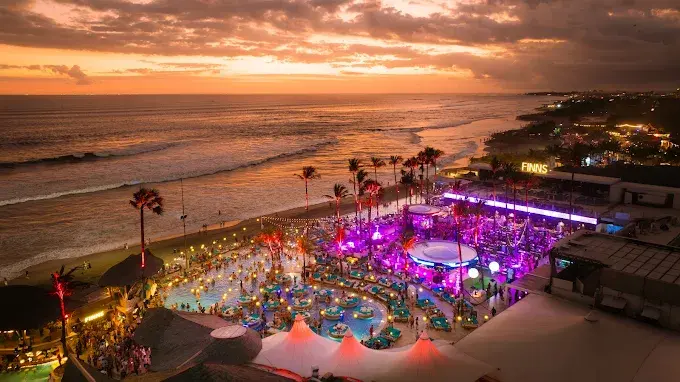 A stunning sunset aerial view of the vibrant Finns Beach Club, showing off the energetic pool party scene that makes it one of the best bars in Bali.