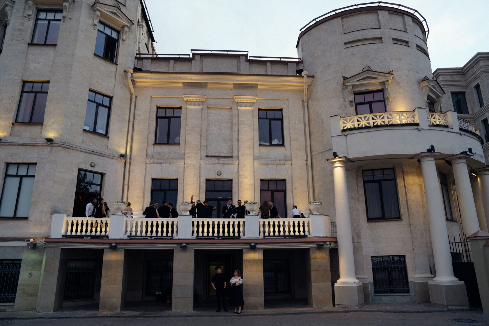 гости на балконе особняка где проходит свадьба 