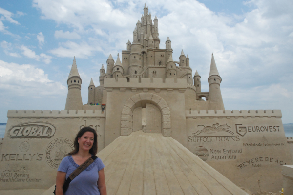 Photo of Karen, standing in front of a ridiculously large sand sculpture.