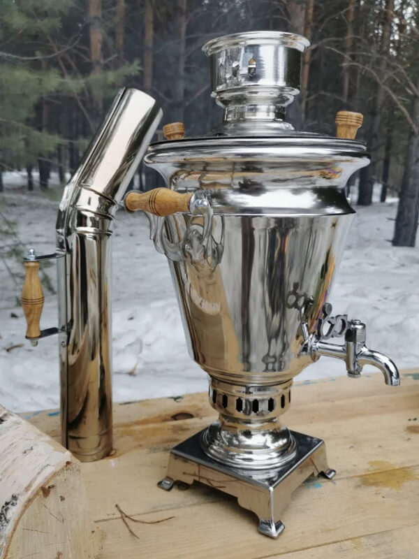 Самовар Стольник с надетой трубой на фоне зимнего леса