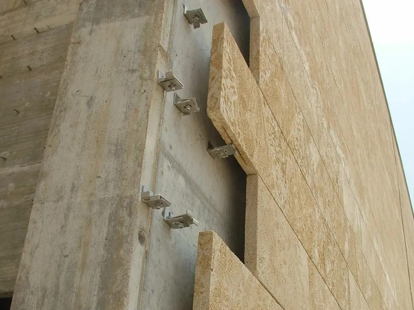 Каменные фасадные плиты на металлических кронштейнах, вид сбоку. Показывает устройство вентилируемого фасада с подсистемой и механическим креплением облицовки.