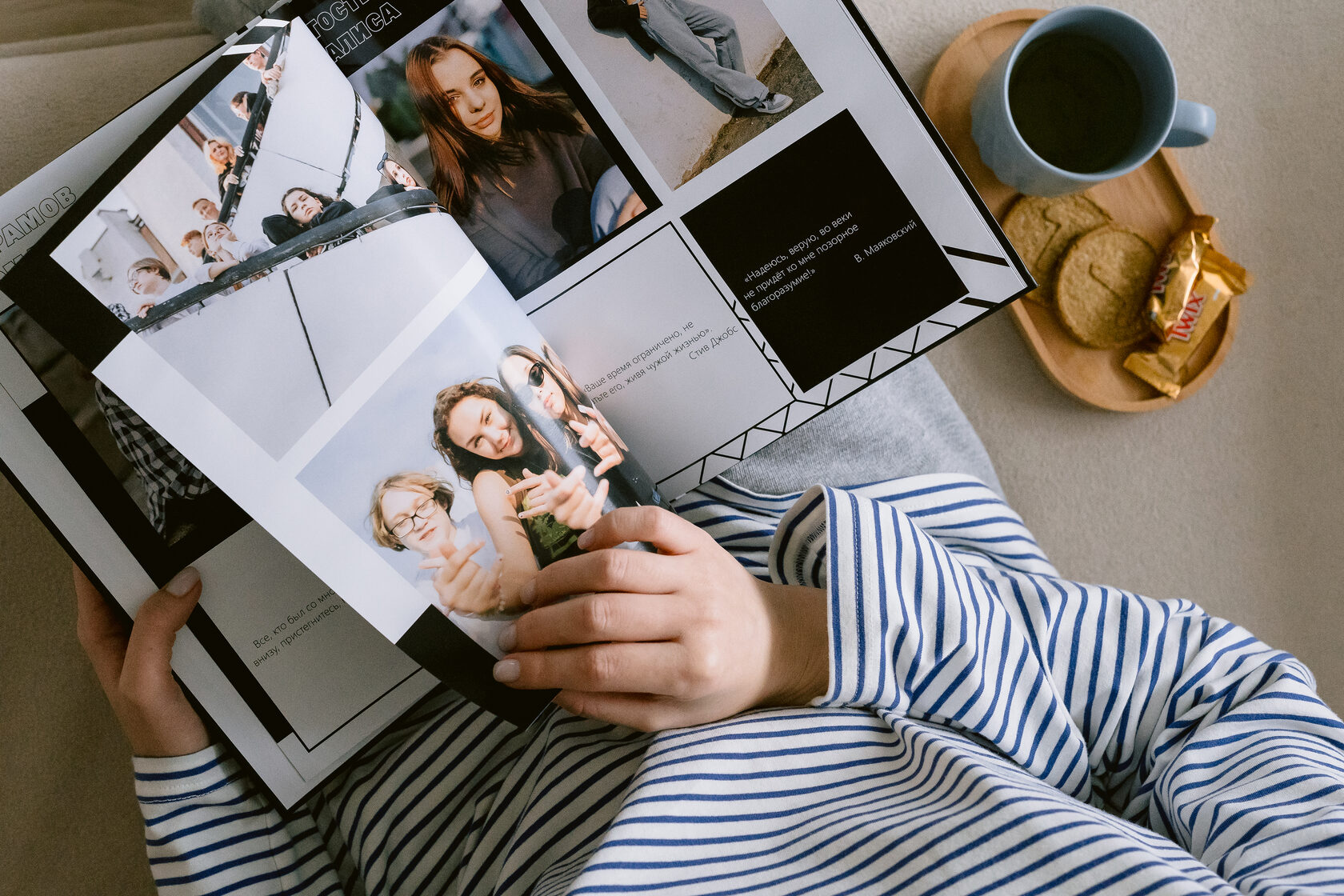 Person reading printed photo album with coffee