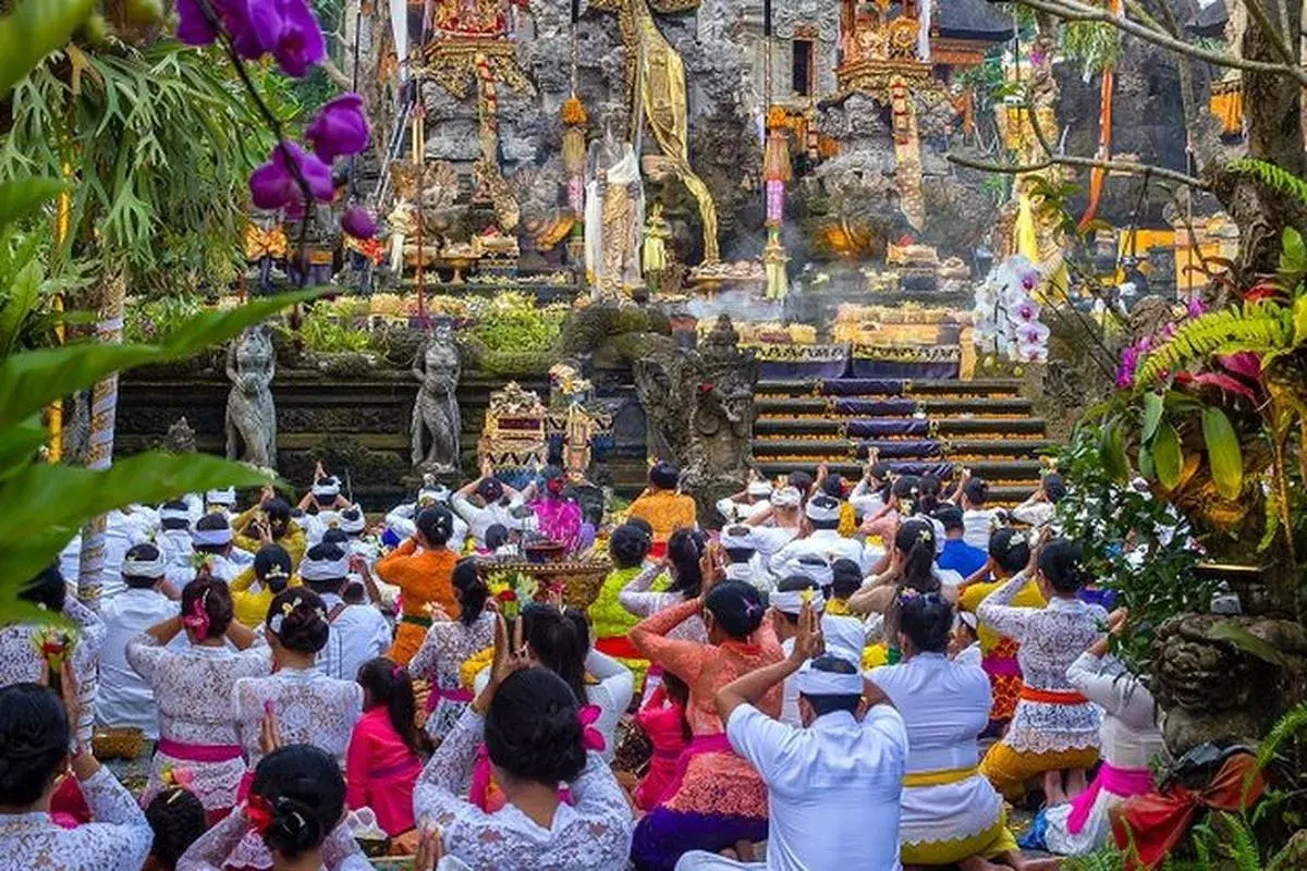 Balinese Hindus wearing traditional white attire gathered in prayer at a temple to celebrate Ngembak Geni, the day immediately following Nyepi.