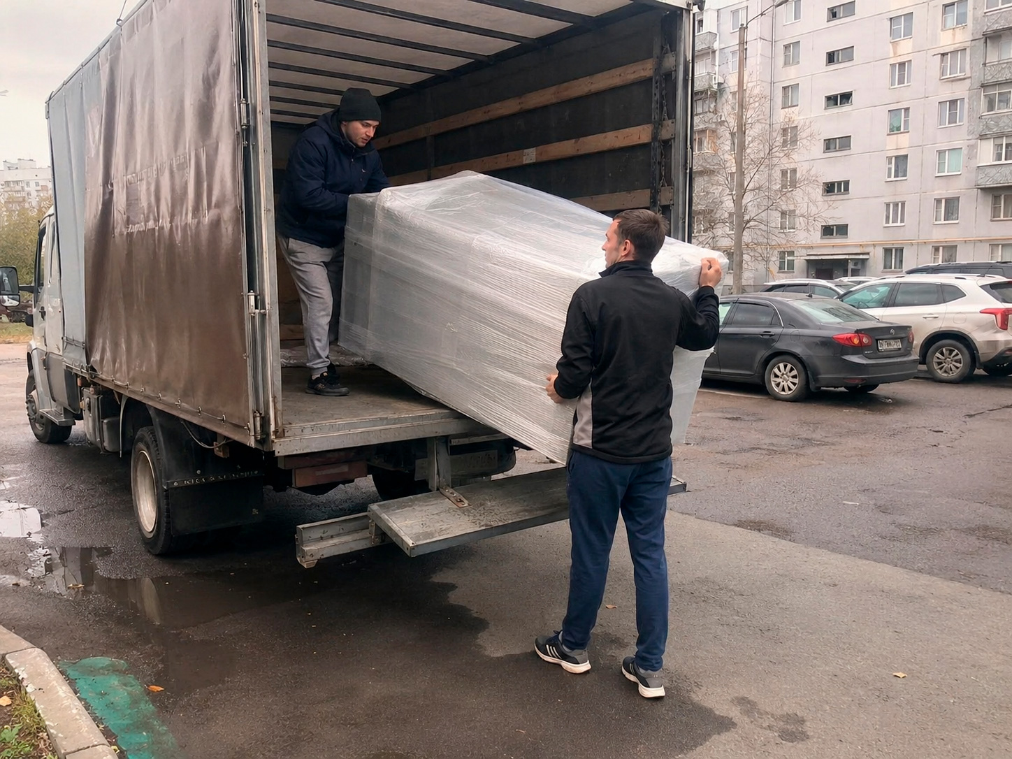 Грузчики загружают упакованную мебель в автомобиль
