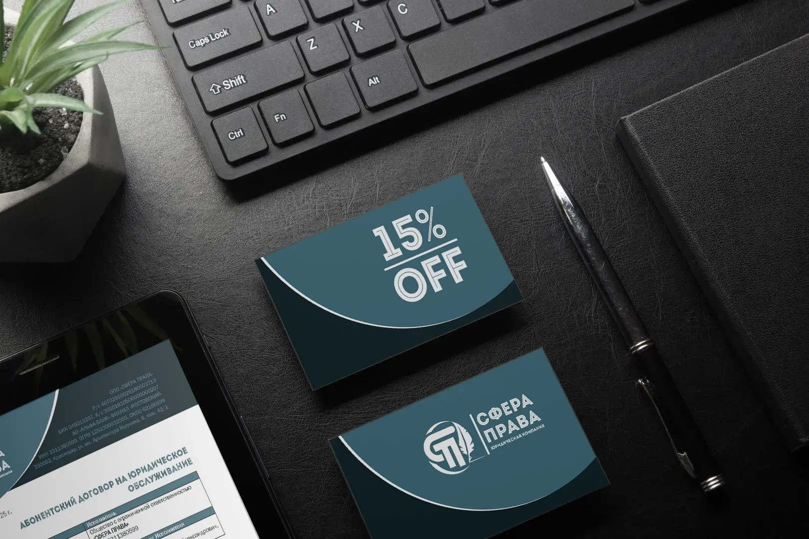 Рабочий стол с визитками компании "Сфера Права", клавиатурой, ручкой и планшетом, на котором открыт договор