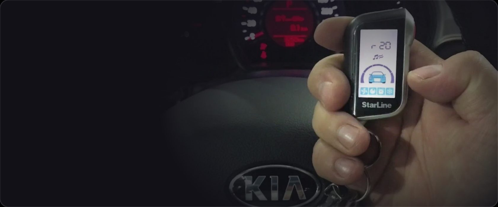 Брелок StarLine с экраном в руке водителя на фоне руля Kia