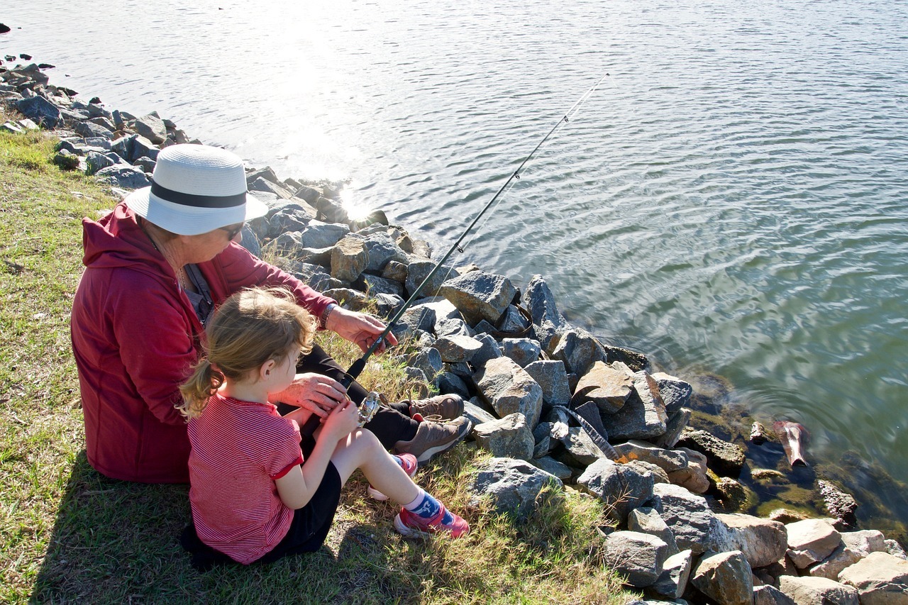 Photo of mentor teaching a young girl how to fish.