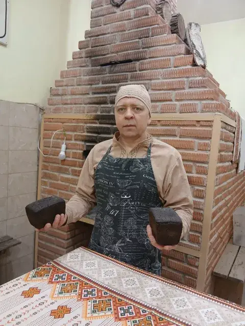 Мастер с буханками блокадного хлеба у печи