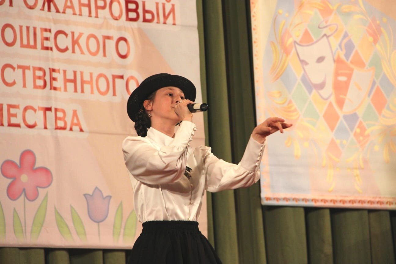 Девушка поёт в микрофон в белой рубашке и чёрной юбке на фестивале