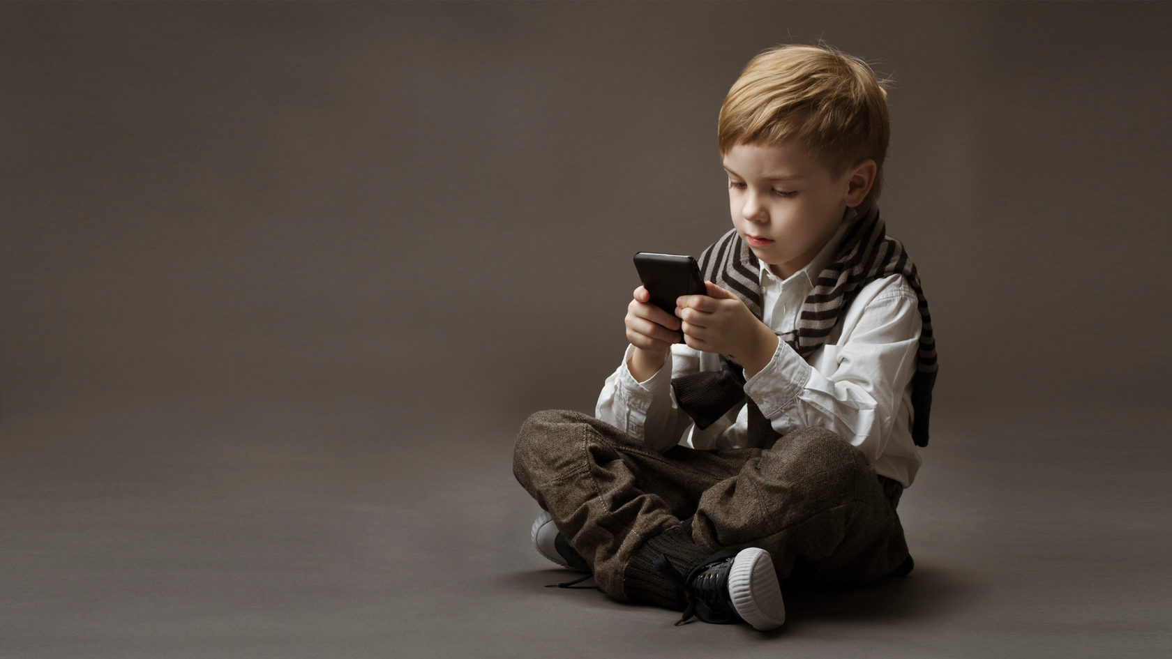 Мальчик сидит в телефоне. Ребенок со смартфоном. Ребенок с телефоном. Мальчик с мобильным телефоном. Ребенок сидит в телефоне.