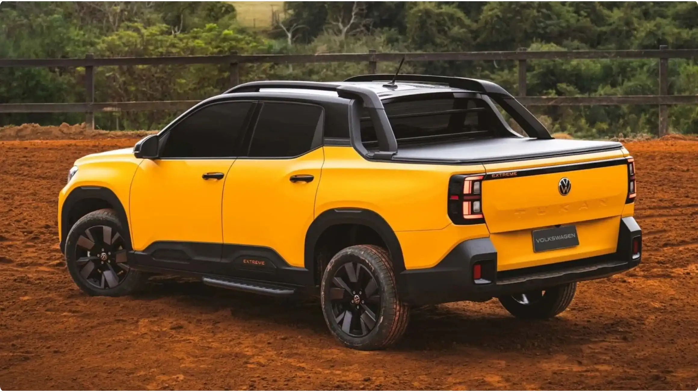 Задняя часть четырехдверного пикапа Volkswagen Tukan Extreme в желтом цвете на грунтовой дороге, черные спортивные дуги и маркировка Extreme.