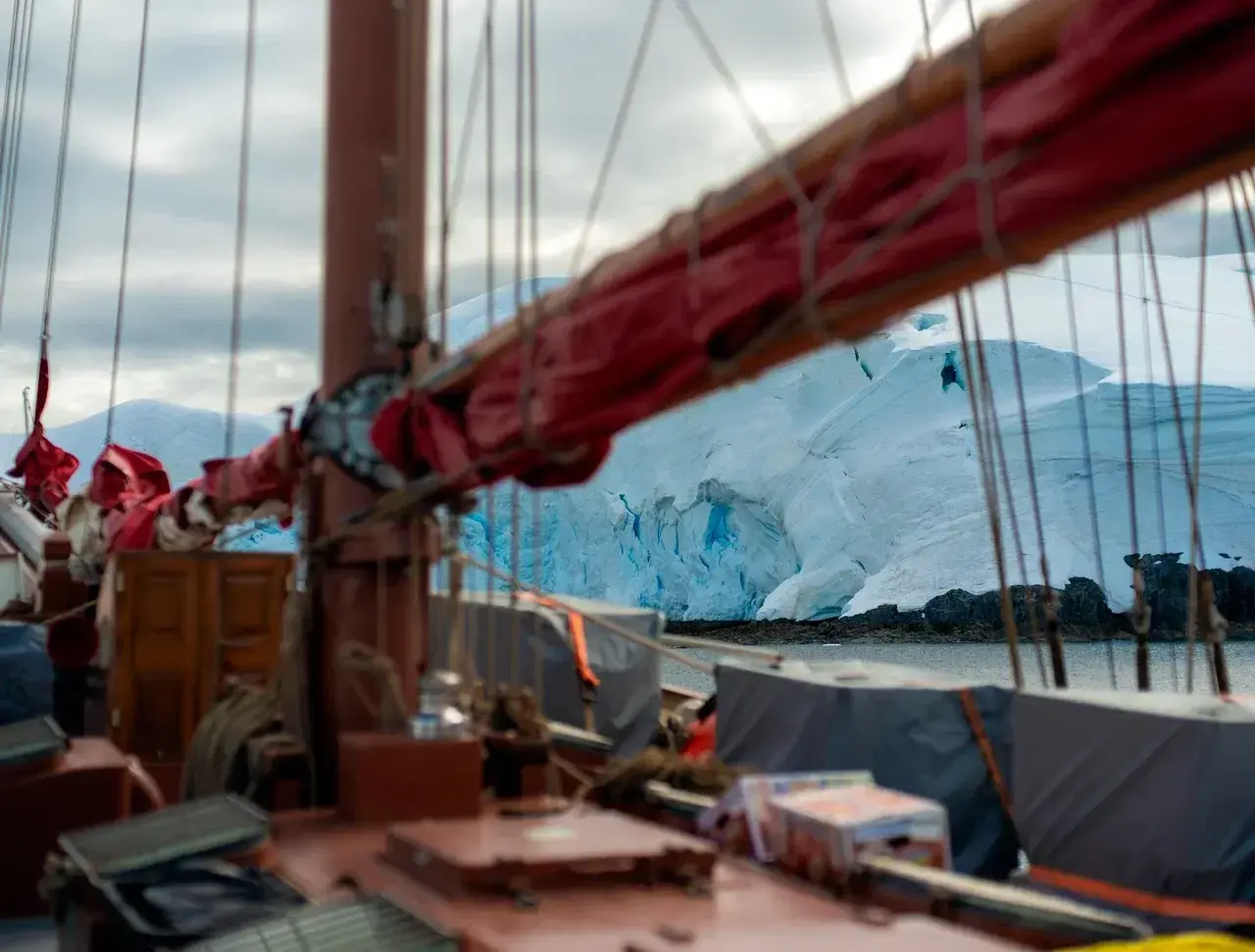 View from the deck of a sailing yacht passing a massive Antarctic iceberg during a polar expedition