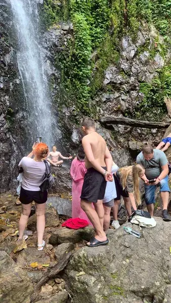 Купание у струи водопада в скалах