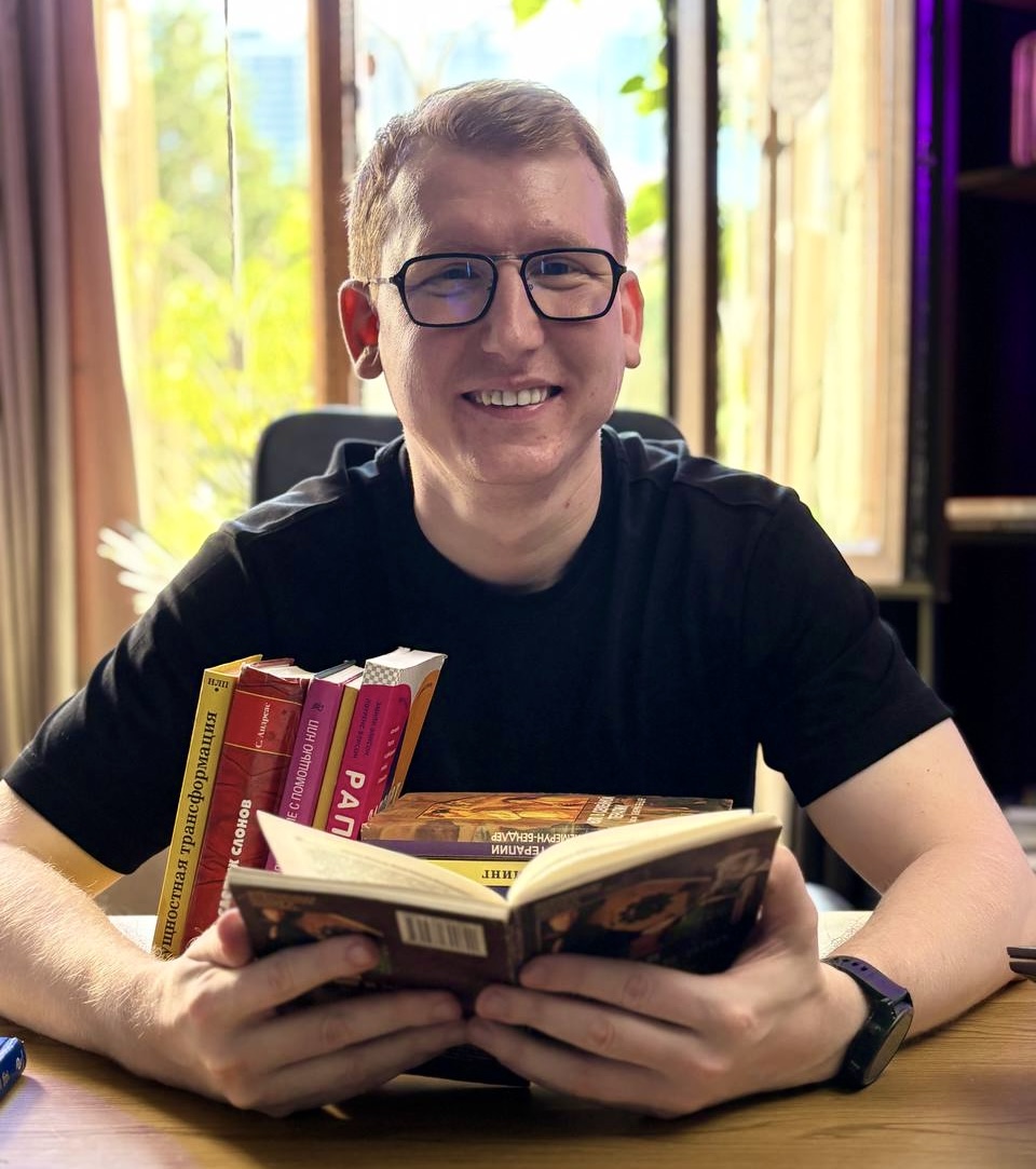 Павел Аглашевич за столом с книгами по НЛП