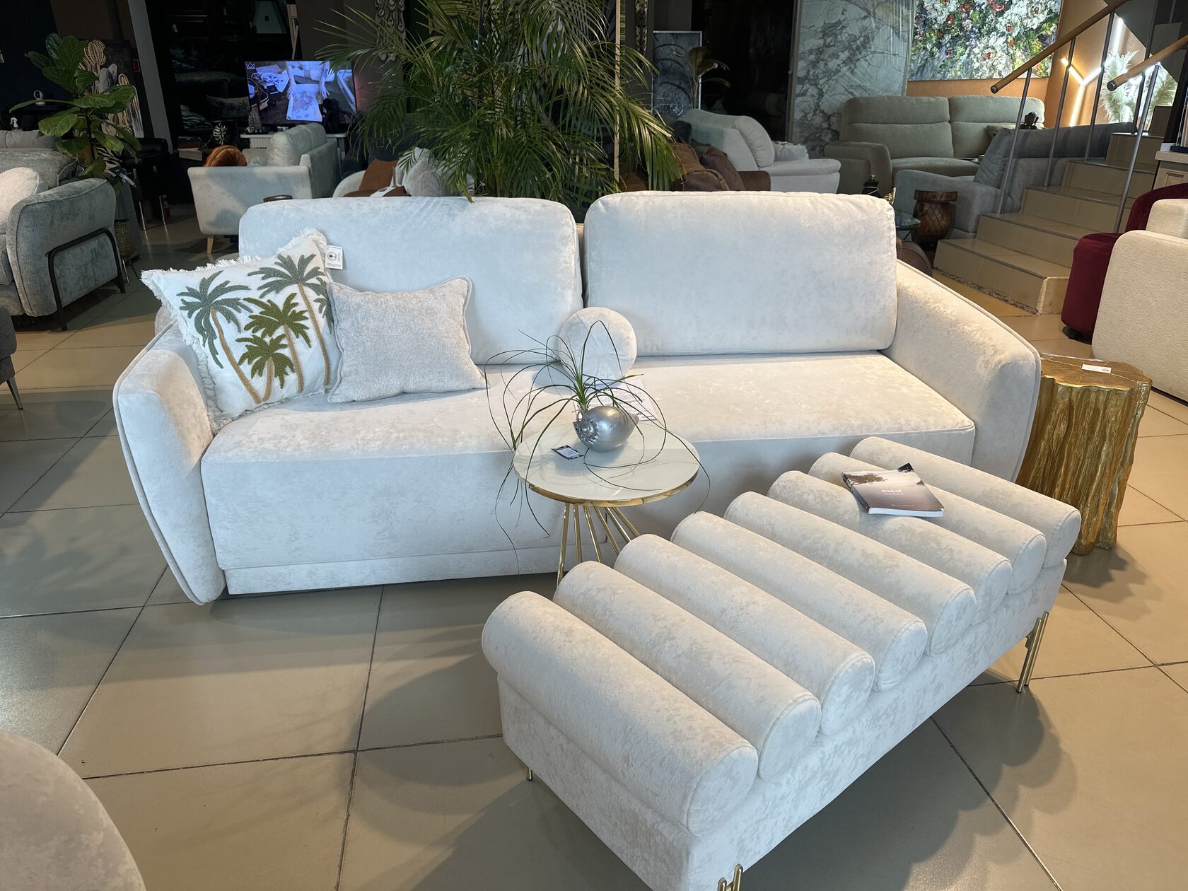 White sofa with palm pillows and ottoman