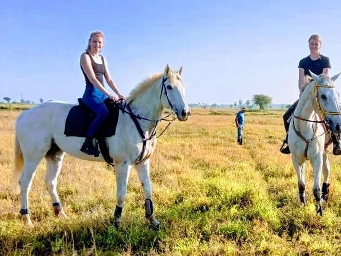 Two guests on white horses in open grassland at Vonfidel Ranch in Sri Lanka.