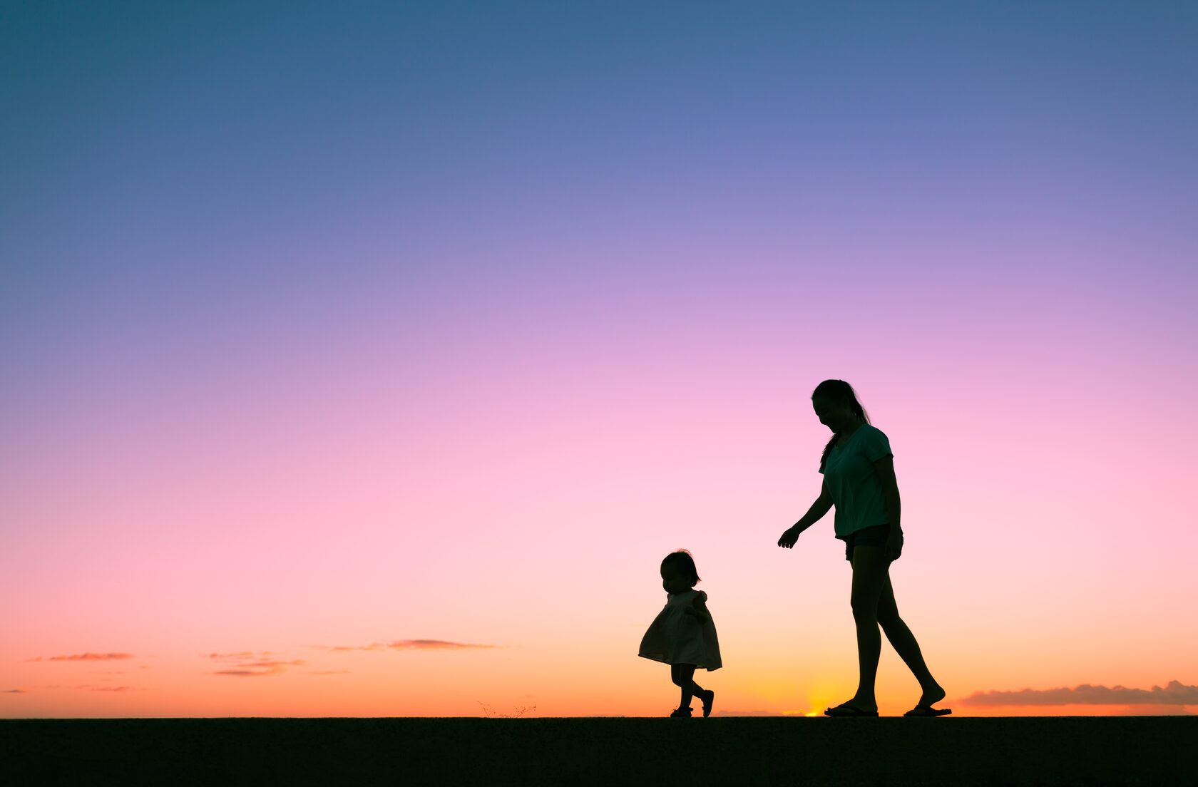 Mother and daughter silhouetted against a beautiful blue purple sky