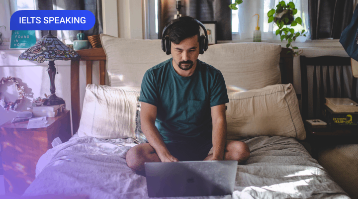 A man with moustache and beard preparing for IELTS at home using a laptop computer and headphones