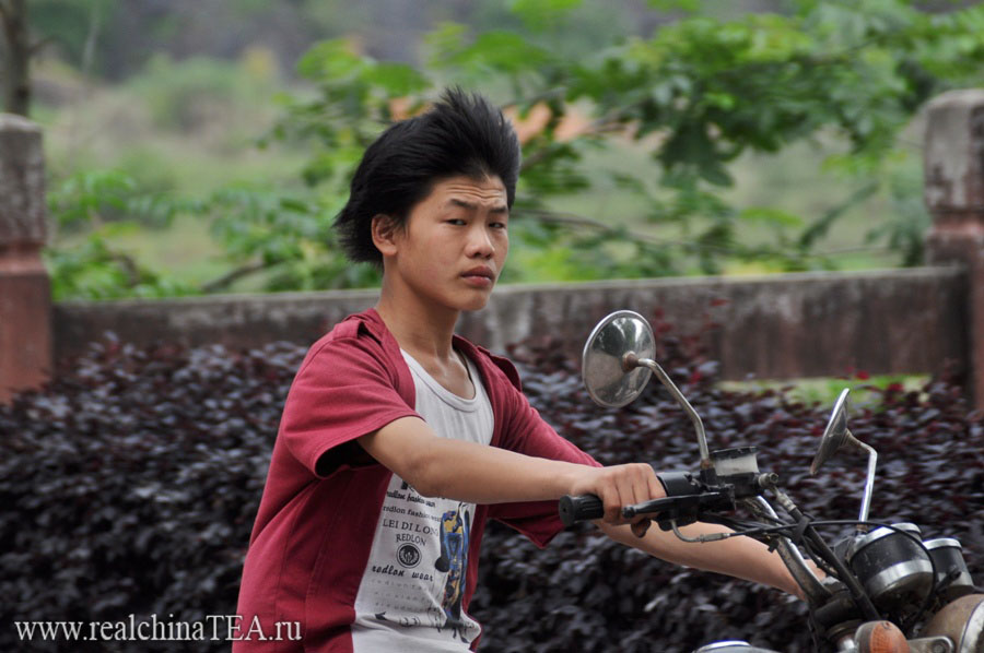 Сын чайного фермера на мотоцикле на платнациях.