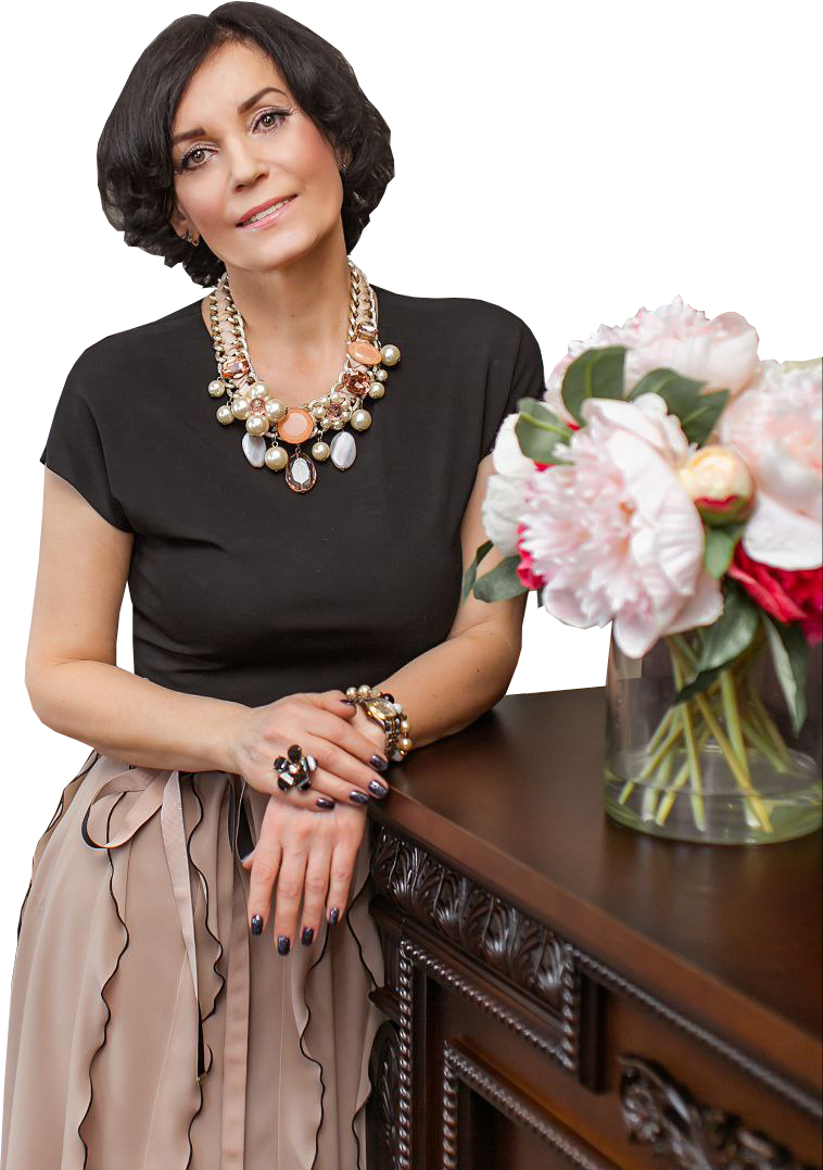 Лариса Окулик, психолог и коуч по детско-родительским отношениям, возле комода с красивыми цветами