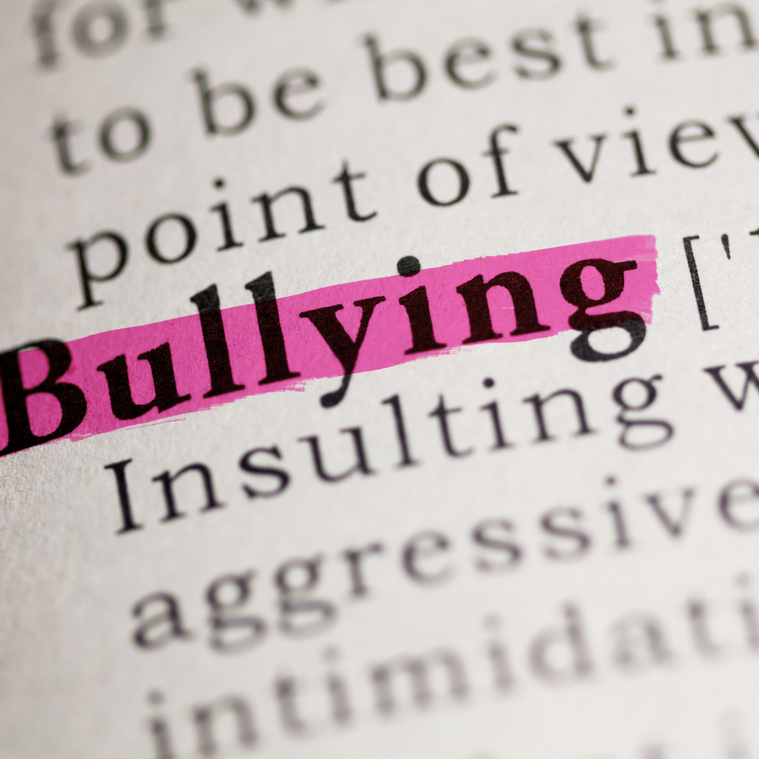 the word bullying is highlighted in pink in a dictionary